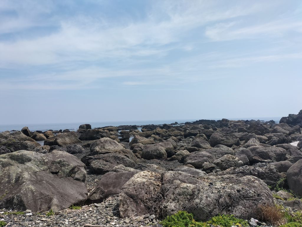 黒みがかった岩が一面に広がる海岸